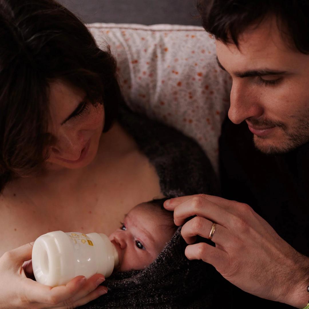 Un papa donne le biberon à son nouveau-né, blotti contre sa maman