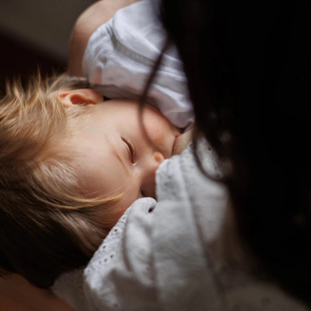 Une maman embrasse son bébé endormi contre elle