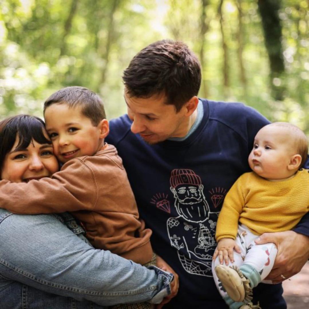 Une famille en forêt, les enfants dans les bras de leurs parents
