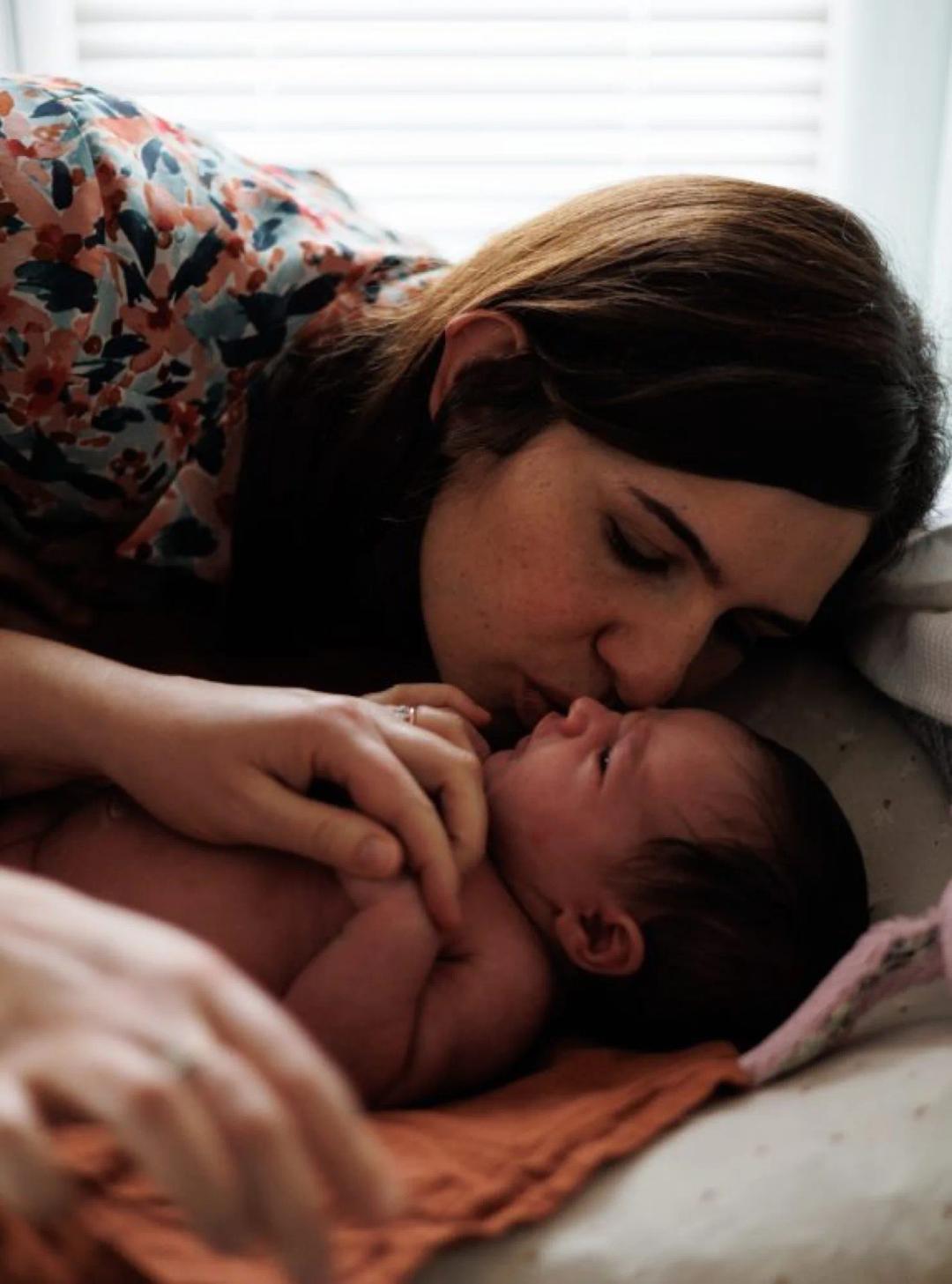 Une maman embrasse son nouveau-né, allongé contre elle