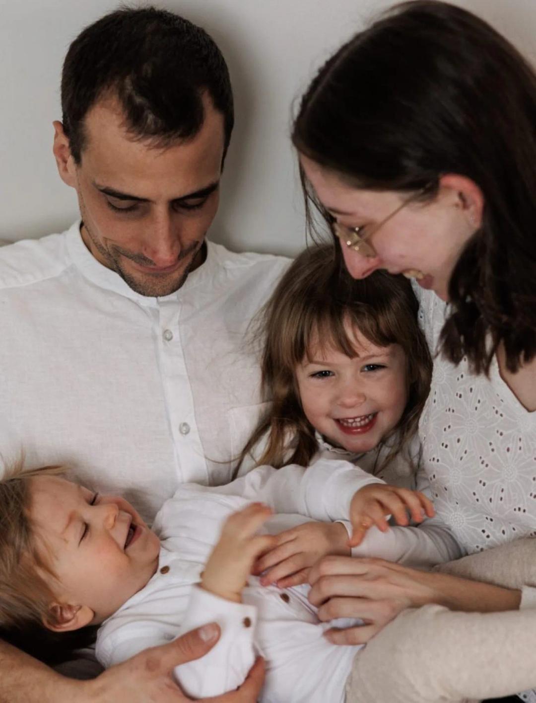 Des parents et leurs deux enfants rient, allongés sur le canapé