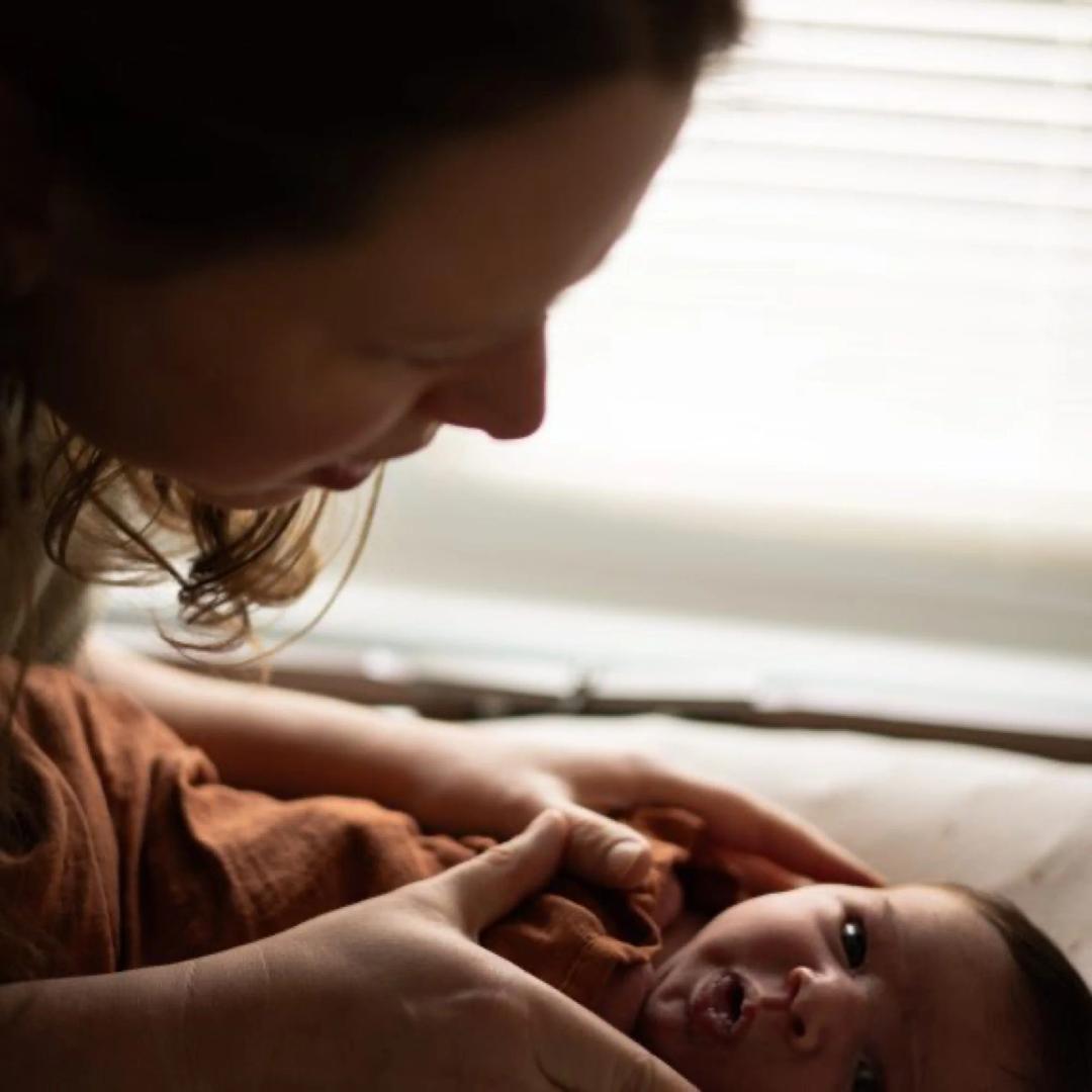 Une maman penchée sur son nouveau-né, dans la lumière d'une fenêtre