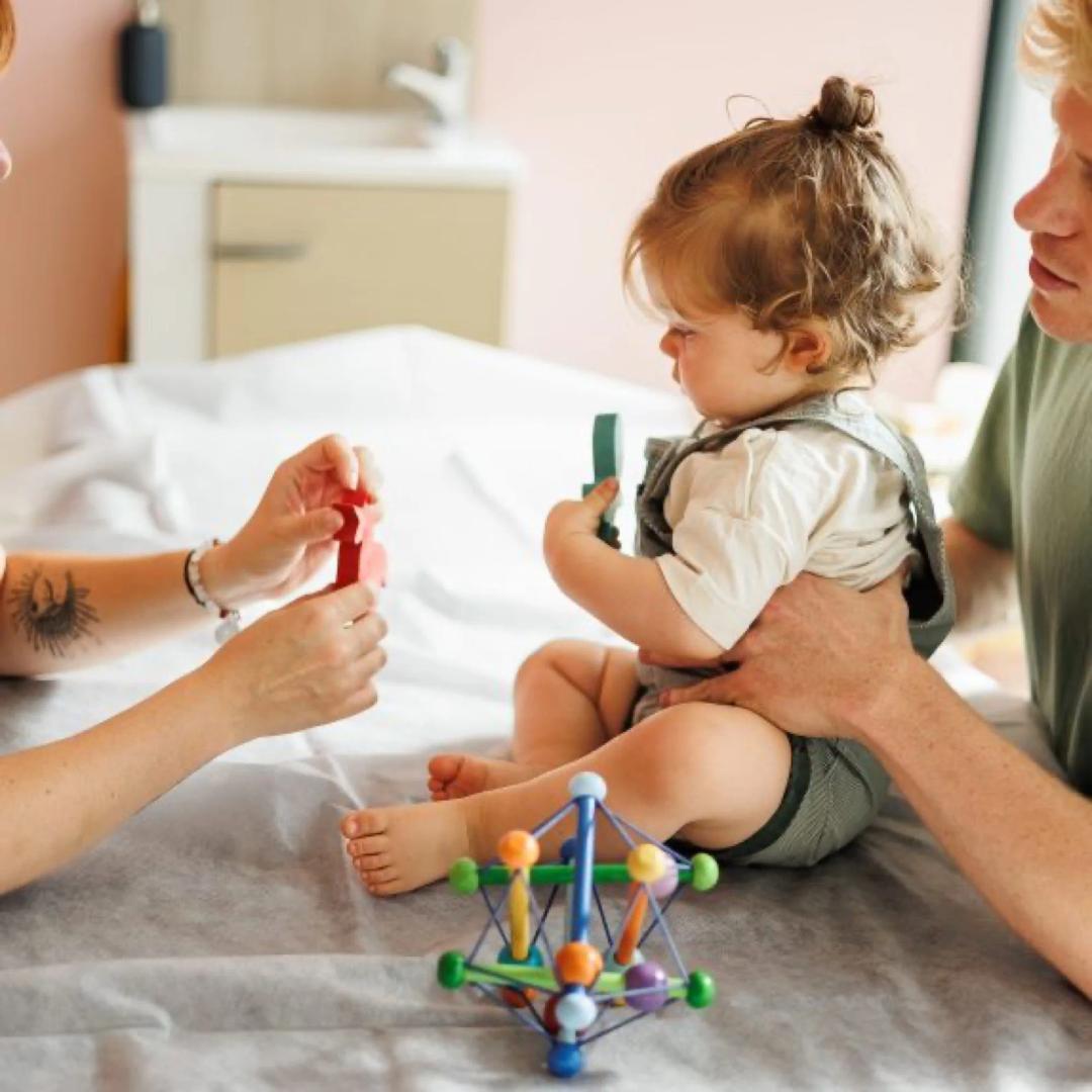 Une praticienne accompagne l'éveil d'un bébé, sous le regard de ses parents