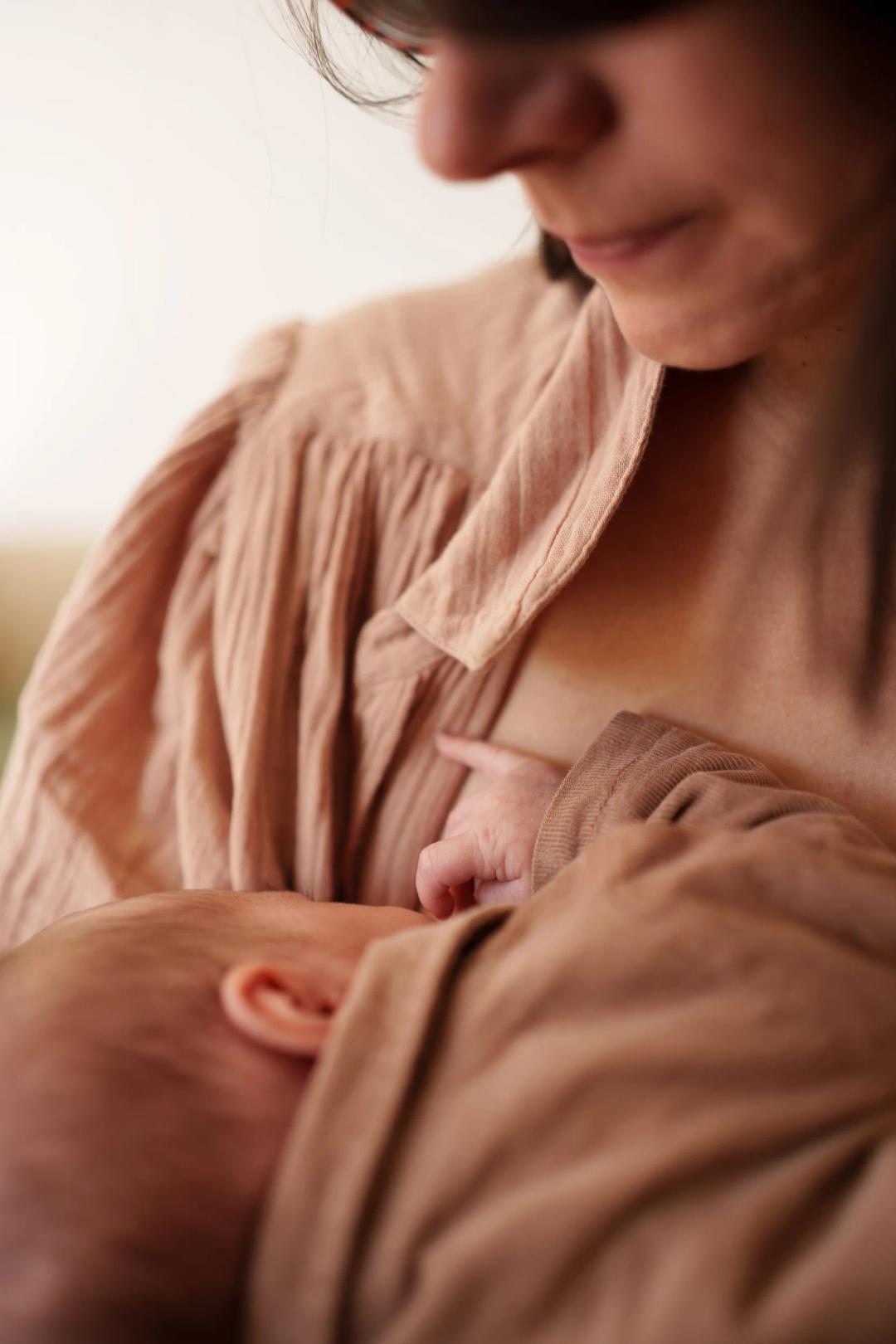 Une maman allaite son nouveau-né, en chemise rose poudré