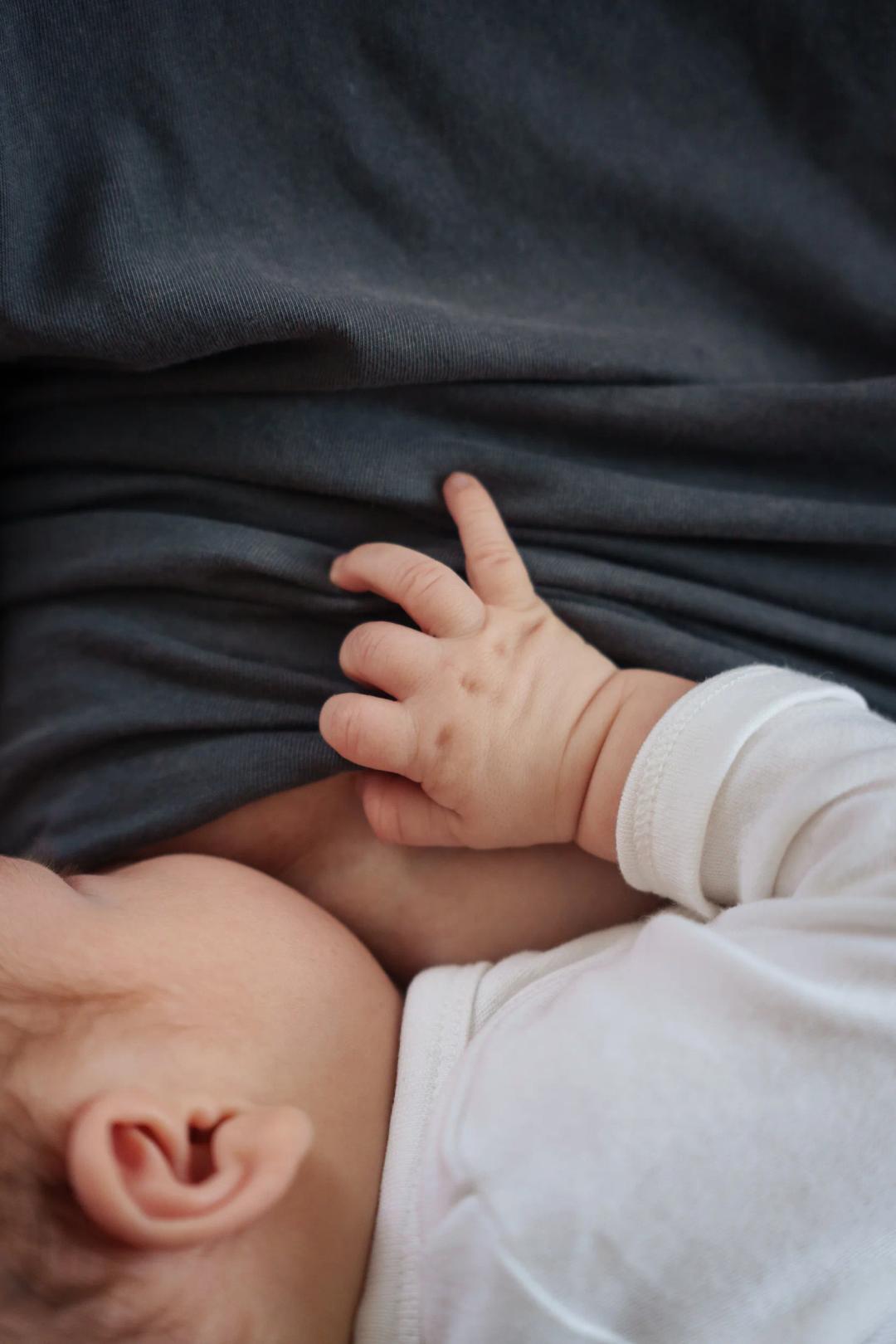 La petite main d'un bébé posée sur le sein de sa maman
