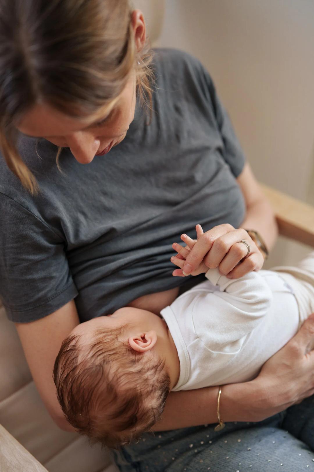 Une maman allaite son bébé, assise dans son fauteuil