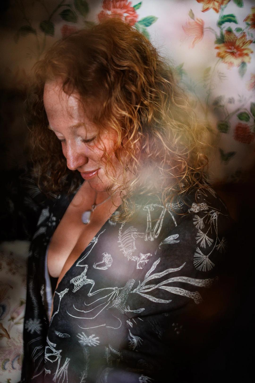 Une femme rousse en kimono fleuri sourit, entourée de fleurs